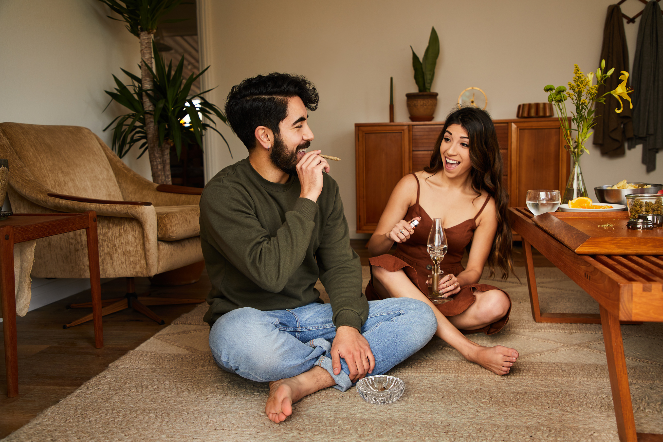 Laughing couple smoking together at home